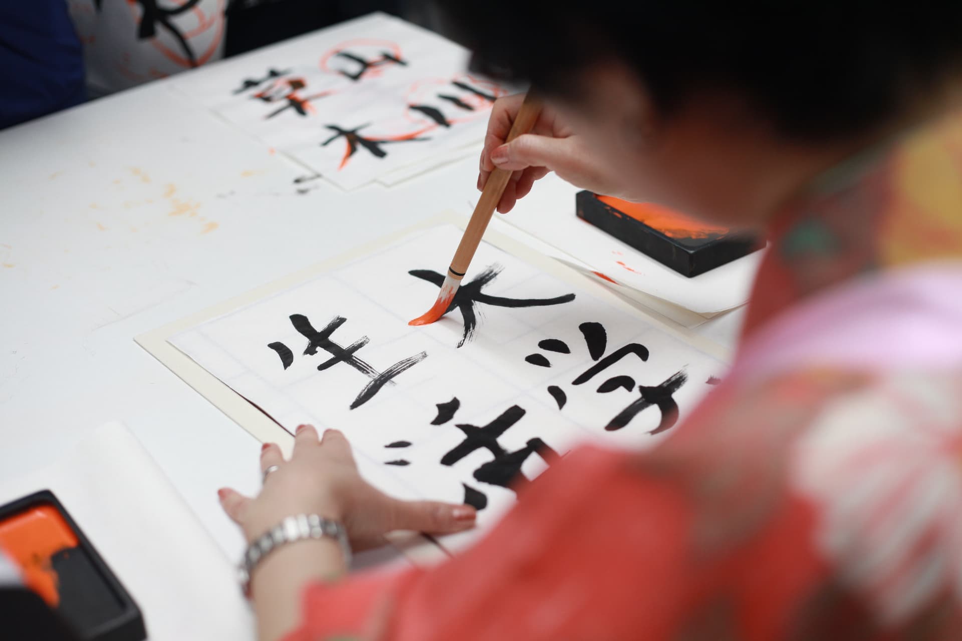 Pessoa praticando caligrafia japonesa com pincel e tinta